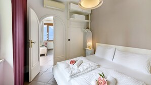 Une chambre d’hôtel avec un lit, une table de chevet avec une lampe, une armoire et une vue sur un balcon.