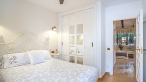 A bedroom with a bed, a nightstand, a wall-mounted lamp, and a wardrobe with a mirrored closet door.
