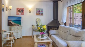 A living room with a sofa, a coffee table with magazines, a painting, a fireplace, and a window with decorative iron bars.