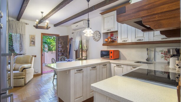 A kitchen with wooden beams, a central island, a microwave, and a sink.