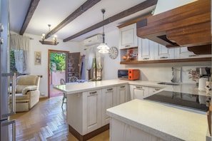 A kitchen with wooden beams, a central island, a microwave, and a sink.