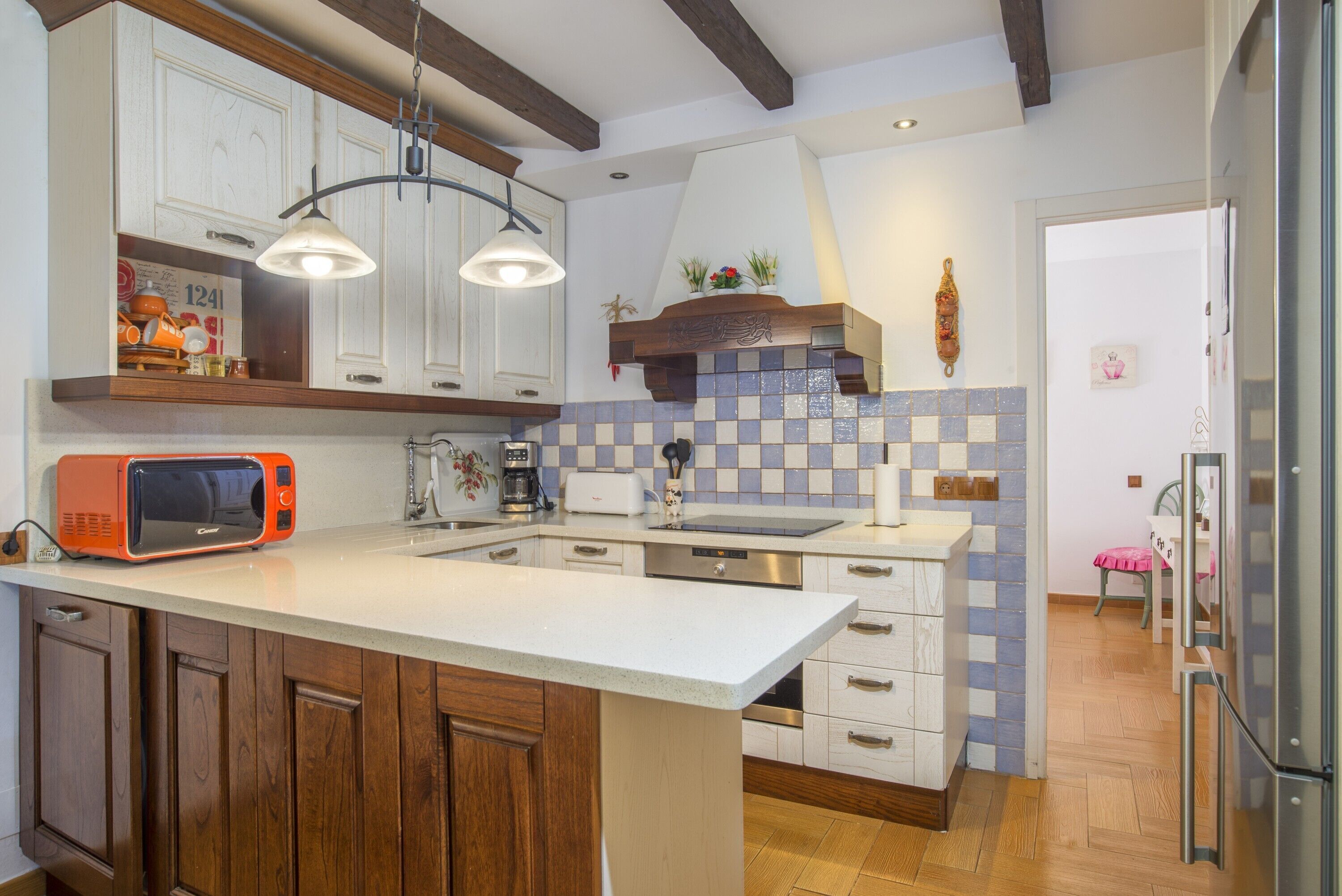 Una cocina con armarios de madera, una encimera blanca, un microondas, un tostador y un lavabo.
