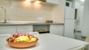 Una cocina con un bol de fruta en la encimera, un lavabo y armarios blancos.