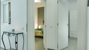 Una habitación de hotel con una cama, una mesita de noche y una puerta que da a otra habitación.
