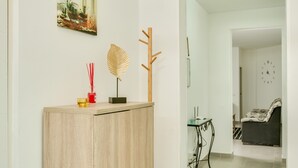Una sala de estar moderna con un armario de madera, un perchero, un reloj de pared y un comedor con mesa y sillas.
