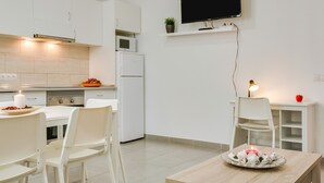 Una cocina moderna con armarios blancos, microondas, refrigerador y comedor con mesa y sillas.