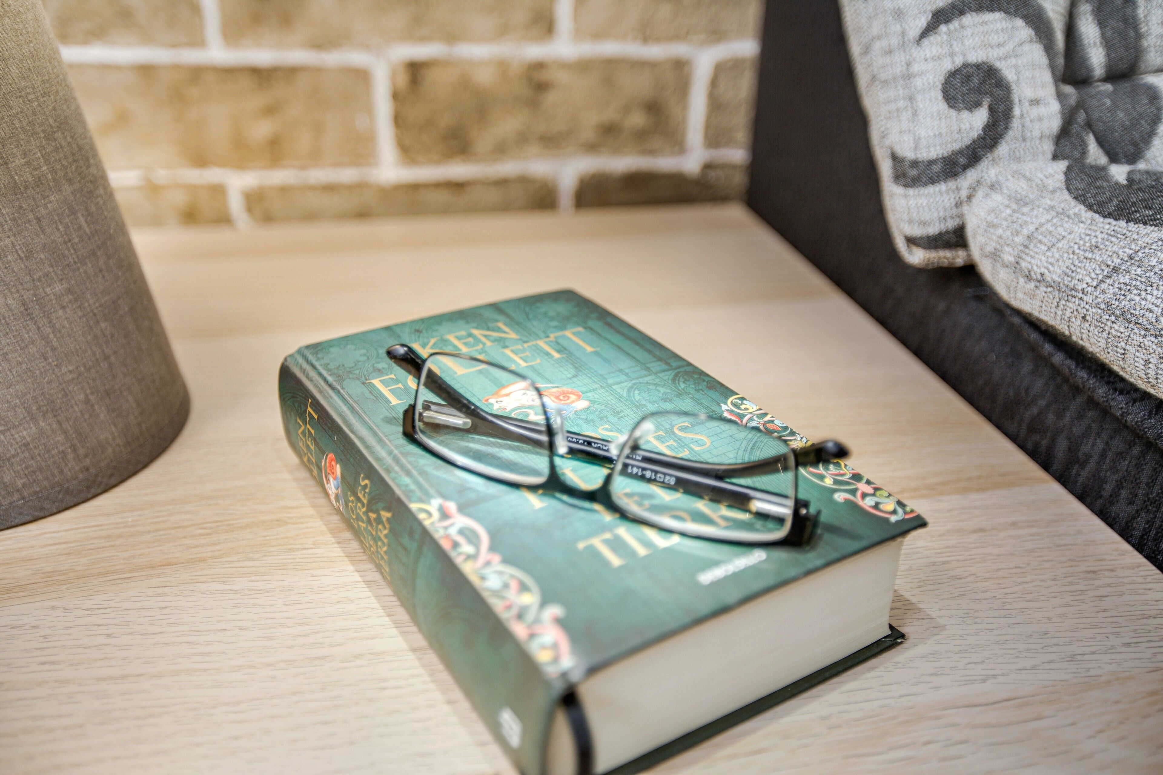 A book titled 'The Hobbit' with glasses on top, placed on a wooden surface.