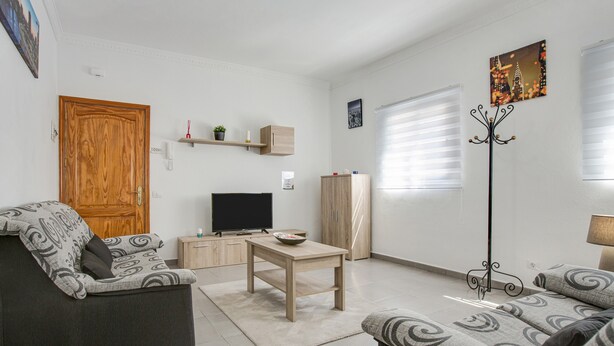 A living room with a sofa, a coffee table, a TV, and a coat rack. - Apartment “2A Francesca” close to the Sea with Wi-Fi & Fans (Vecindario)