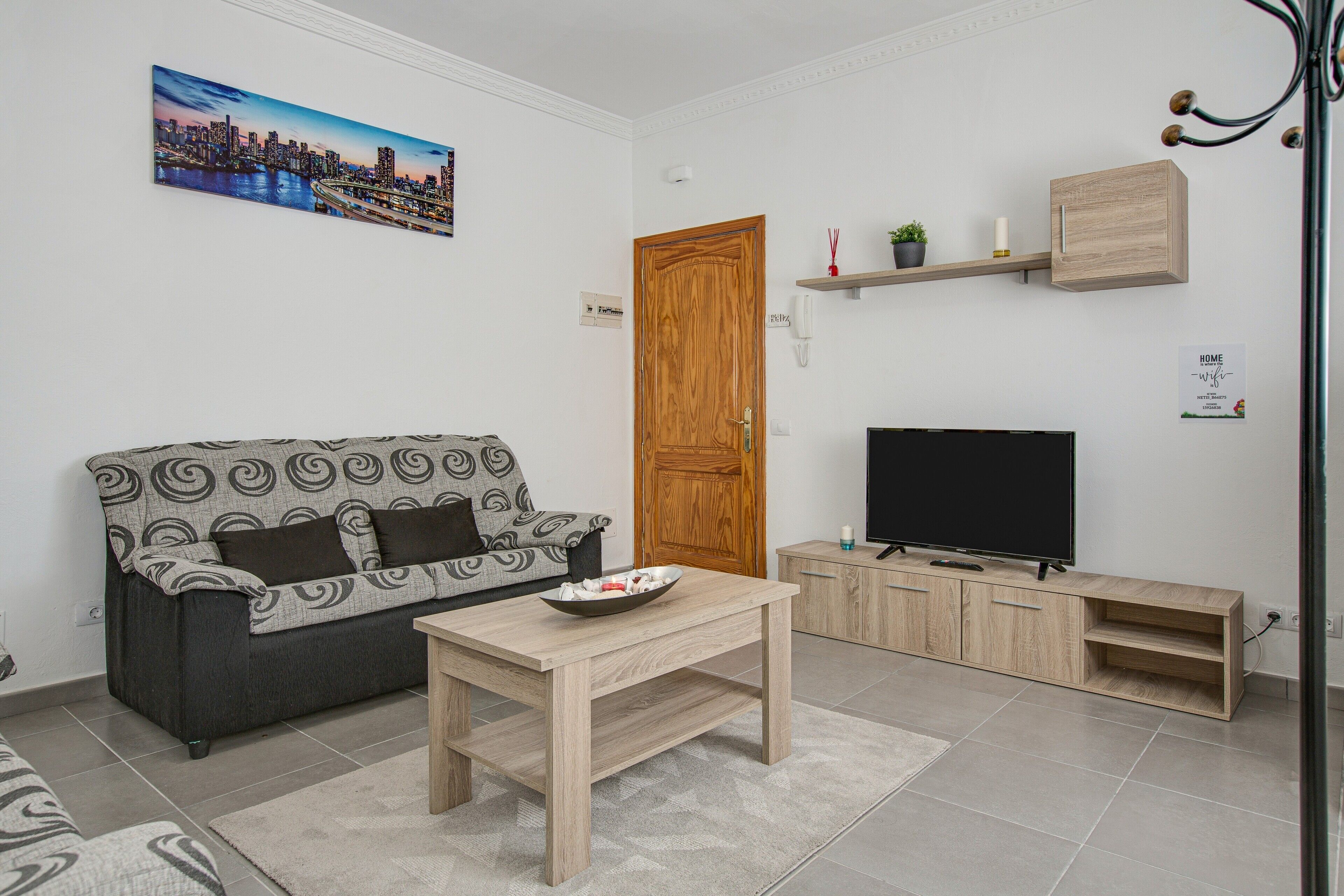 Una sala de estar con un sofá, una mesa de centro, un televisor y un mueble de madera.