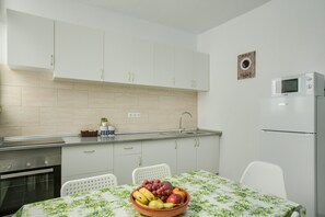 A modern kitchen with white cabinets, a microwave, and a fruit bowl on the table. - Cosy Apartment “2B El Amore” close to the Sea with Wi-Fi & Fans (Vecindario)