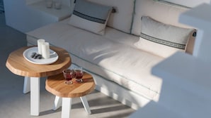 A modern living room with a white sofa, two wooden side tables, and a glass coffee table. - Salty villa with private Pool & Sea view (Santorini)
