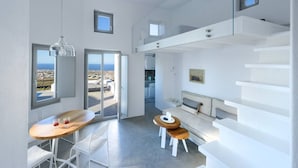A modern interior with a dining area, a sofa, and a staircase. - Salty villa with private Pool & Sea view (Santorini)