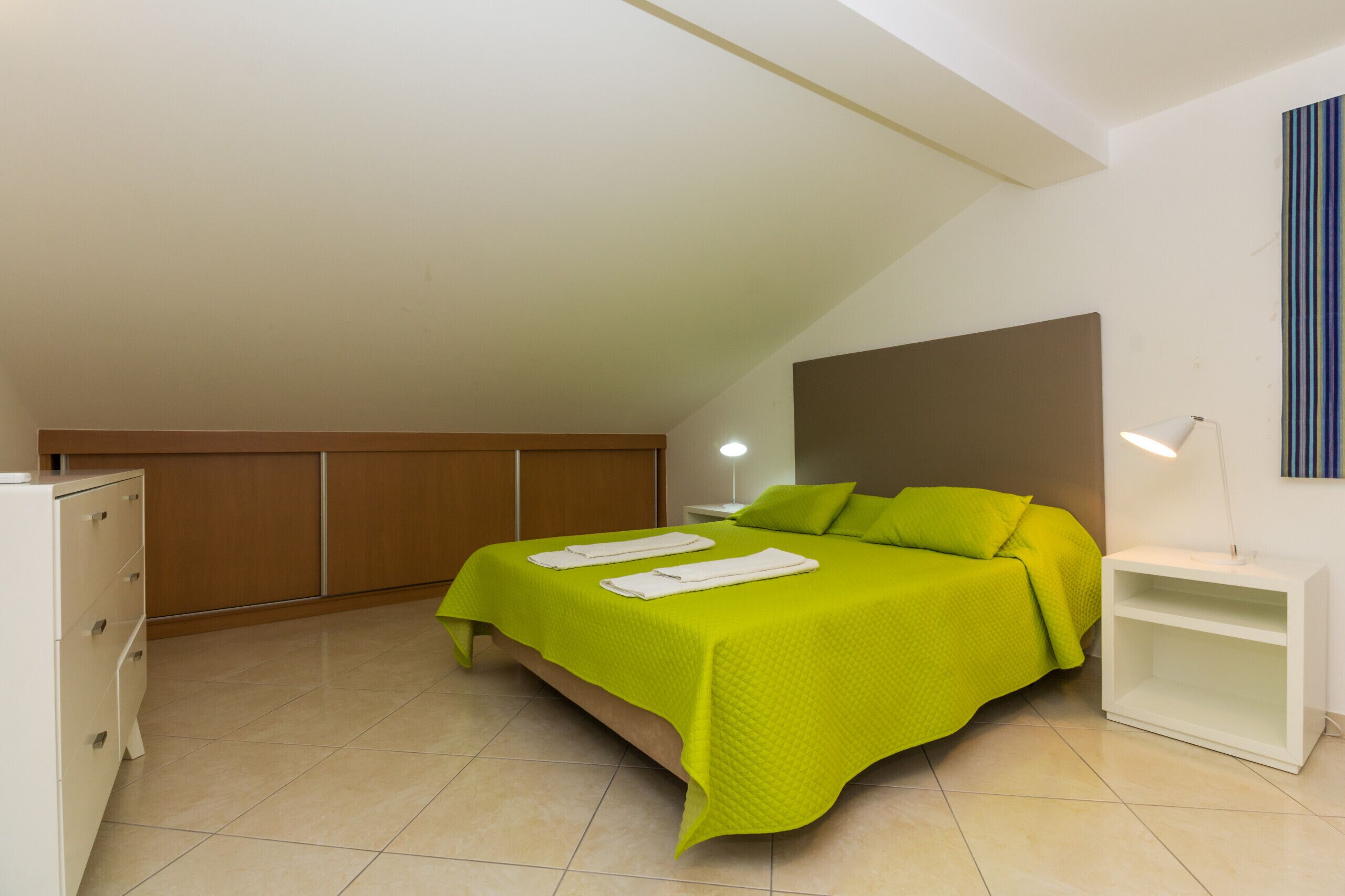 A modern bedroom with a bed, bedside table, and a wardrobe.
