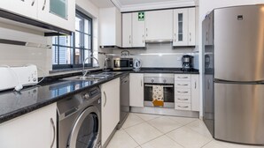 A modern kitchen with stainless steel appliances, a built-in washing machine, and a coffee maker.