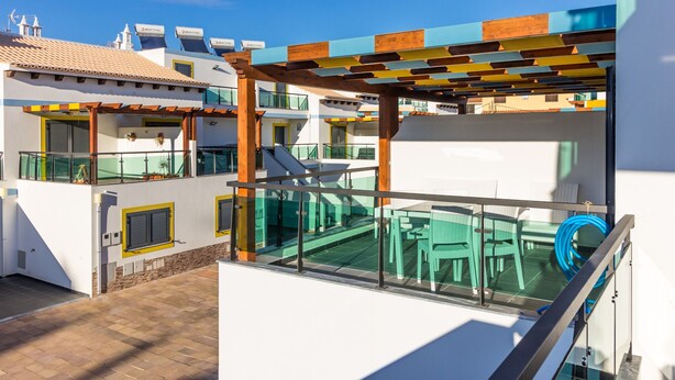 A rooftop terrace with outdoor seating, a pool, and a view of adjacent buildings.