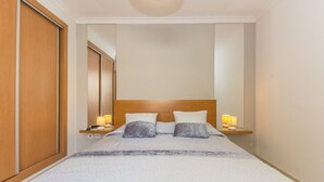 A bedroom with a bed, bedside lamps, and a wardrobe.