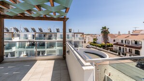 A multi-story residential building with balconies, a tiled terrace, and a view of the surrounding neighborhood.