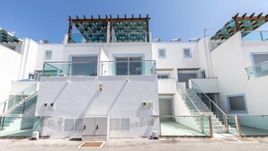 A modern building with a central staircase, glass railings, and a covered outdoor area.