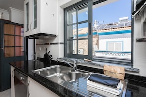 A modern kitchen with a large window, stainless steel sink, and a view of a traditional building outside.
