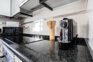 Eine moderne Küche mit einer schwarzen Induktionskochplatte, einer Kaffeemaschine und Holzkocherutensilien.