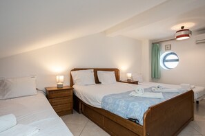 Ein Schlafzimmer mit einem großen Bett, zwei Nachttischen, einem Schranken und einem Fenster mit Vorhängen sowie einer Deckenleuchte.