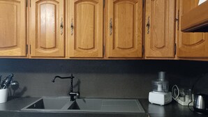 A kitchen with wooden cabinets, a stainless steel sink, and a coffee maker. - CASA DI MAMMA near gorges de L'ASCO corsican center, river, sea. (Moltifao)