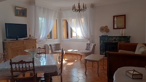A living room with a TV, a fireplace, and a dining area with a table and chairs. - CASA DI MAMMA near gorges de L'ASCO corsican center, river, sea. (Moltifao)
