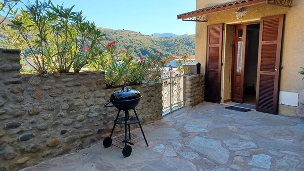 A stone patio with a barbecue grill, a stone wall, and a view of a hilly landscape. - CASA DI MAMMA near gorges de L'ASCO corsican center, river, sea. (Moltifao)