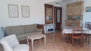 A living room with a sofa, a small table, a chair, and a dining table with chairs. There is a cabinet with decorative items and a mirror. - CASA DI MAMMA near gorges de L'ASCO corsican center, river, sea. (Moltifao)