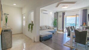 Ein modernes Wohnzimmer mit Sofa, Esstisch und Stühlen. Es gibt einen Balkon mit Blick.