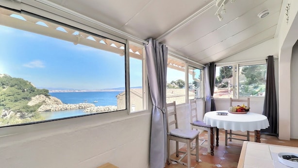 Ein Balkon mit Tisch und Stühlen mit Blick auf eine Küstenlandschaft.