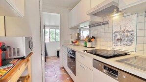 Eine moderne Küche mit weißen Schränken, einem Einbauofen, einem Geschirrspüler und einer Mikrowelle.