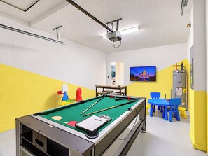 A pool table in a room with a yellow and white wall, a projector mounted on the ceiling, and a heater on the wall. - Family Disney Retreat / Entertainment Room / Console Provided (Kissimmee)