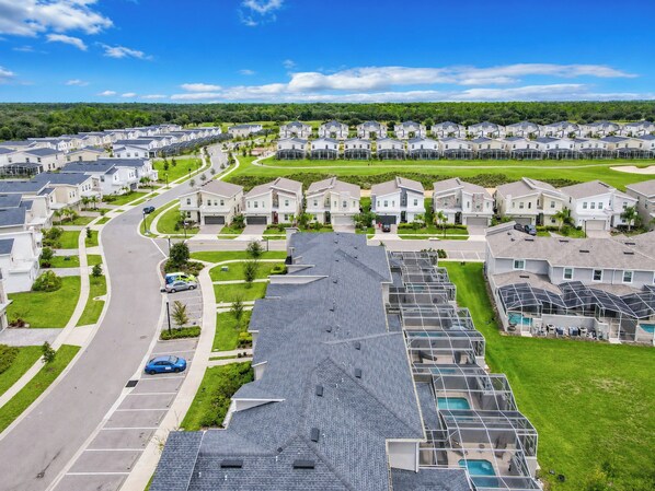 A residential area with modern houses, a curved road, and a swimming pool area.