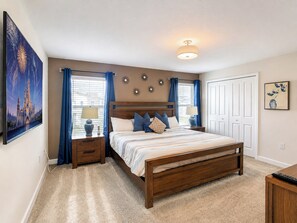 A bedroom with a wooden bed, two bedside tables, a nightstand, a ceiling light, a window with curtains, and wall decorations.