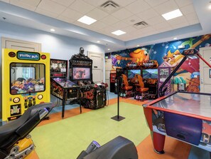 A gaming arcade with various machines, including a yellow bus-themed claw machine and multiple arcade games.