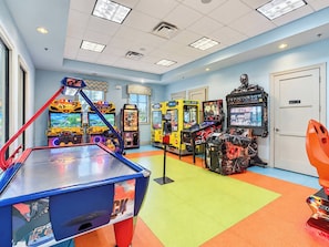 An indoor arcade with various gaming machines, a pool table, and a door.