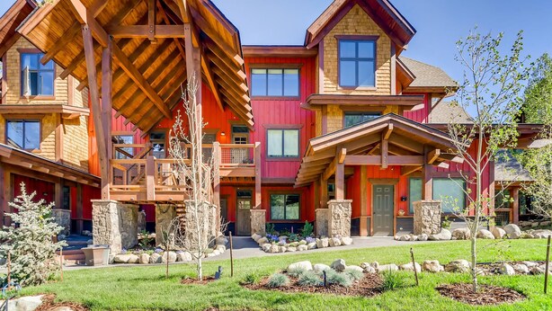 A multi-story building with a prominent wooden structure, stone pillars, and a well-maintained garden. - New Complex Close to Shuttle for Easy Access to Resort w/ Private Hot Tub! (Keystone)