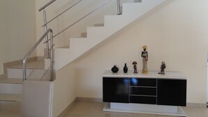 Uma escadaria com guarda-corpo de metal e um console preto e branco com objetos decorativos.