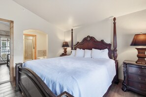 A four-poster bed with a white bedspread, a nightstand with a lamp, and a dresser with drawers. - Adventure Hub~Nordic Ski, Snowmobile & Snow Shoeing Villa 3050-2 (Midway)