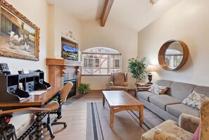 A furnished living room with a sofa, armchair, coffee table, and a desk with a computer.