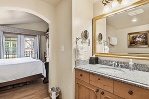 A hotel room with a bed, a bathroom with a sink, and a large mirror.