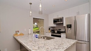 Eine moderne Küche mit Granit-Arbeitsplatten, Edelstahlgeräten und Pendelleuchten.
