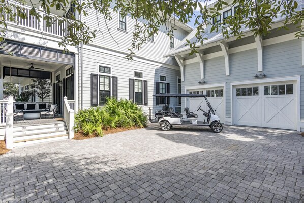 Une maison à deux étages avec un porche couvert, un garage et une voiturette de golf garée dans l’allée.