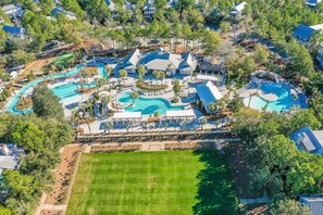 Vue aérienne d’un complexe hôtelier doté de plusieurs piscines, d’une vaste pelouse et d’arbres environnants.