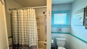 Un baño con inodoro, bañera y cortina de ducha.