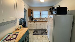 Cocina compacta con armarios blancos, microondas y refrigerador.