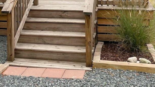A wooden deck leading to a cottage with a sign reading "Cattail Cottage."