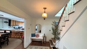 A home interior with a dining area, kitchen, staircase, and a living room with a rug and a potted plant. - Miss Agnes - Water Front 3BR home PET FRIENDLY, NO LINENS PROVIDED (Chincoteague)