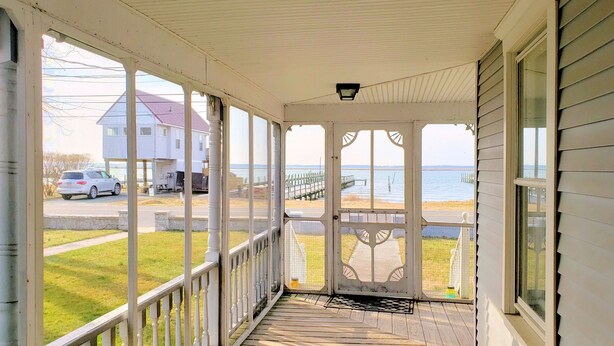 A covered porch with a view of the beach and a wooden dock. - Miss Agnes - Water Front 3BR home PET FRIENDLY, NO LINENS PROVIDED (Chincoteague)